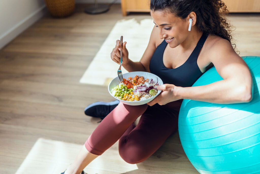 Sporty young woman eating healthy while listening to music sitti